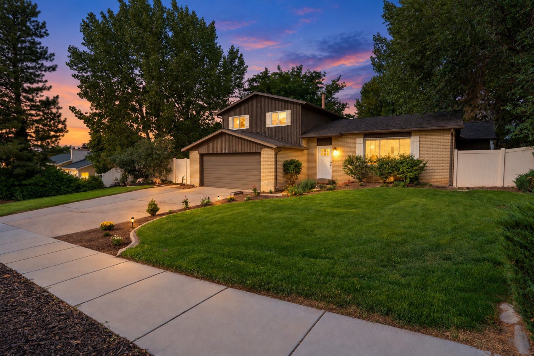 Twilight exterior of the renovated brick and cedar tri-level at 2407 E Hunts End Drive, Sandy