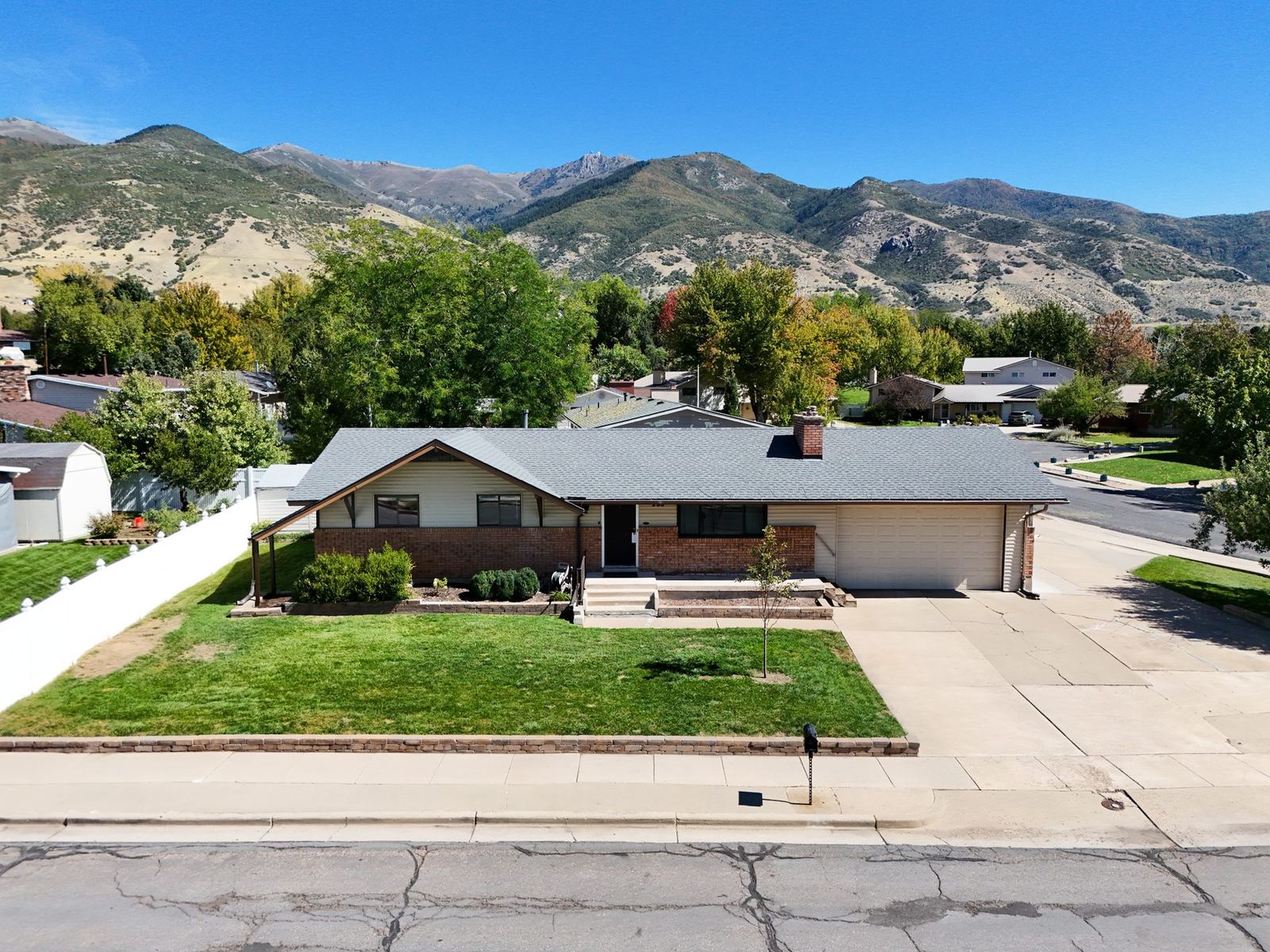 Aerial view of 235 S 900 E, a brick rambler in Kaysville, with the Wasatch Front behind it